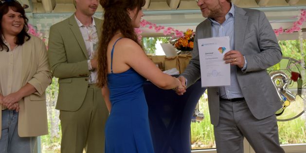 Schulleiter überreicht einer Absolventin der BG22 das Abschlusszeugnis mit Handschlag.